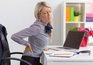 Femme ayant mal au dos assise dans son bureau